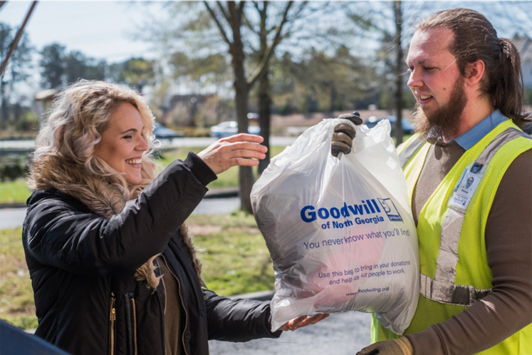 Women handing Goodwill employee a bag of donations