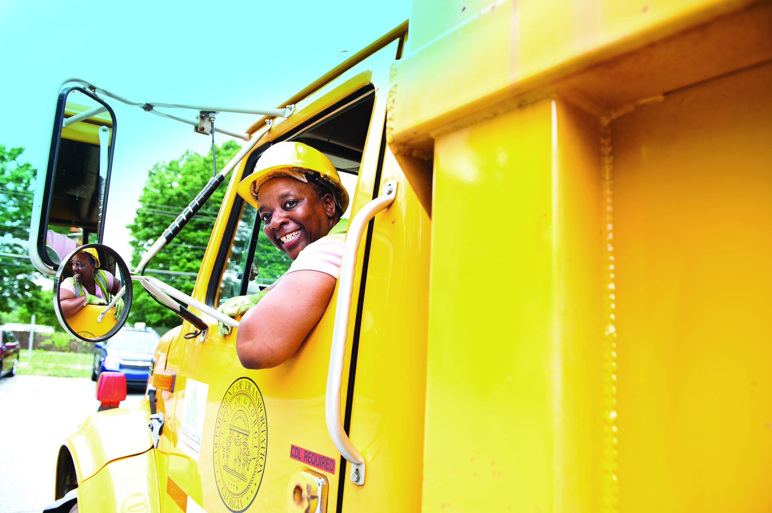 women in hard hat driving a yellow truck