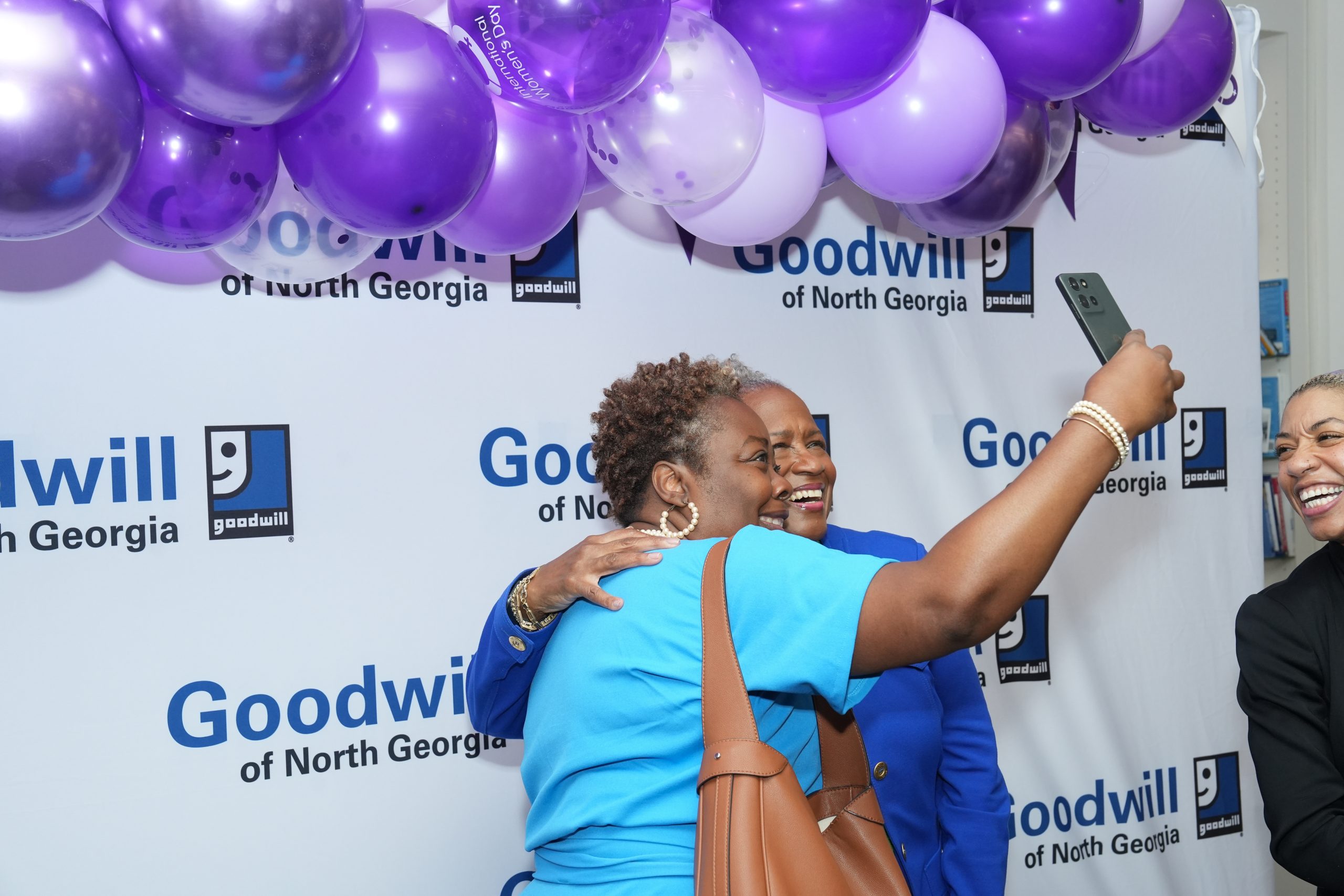 Two women taking a selfie together in front of event backdrop